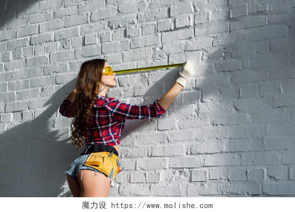 性感妇女用工具皮带测量白色砖墙
